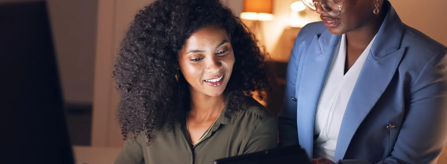 Two colleagues smiling while looking at a laptop